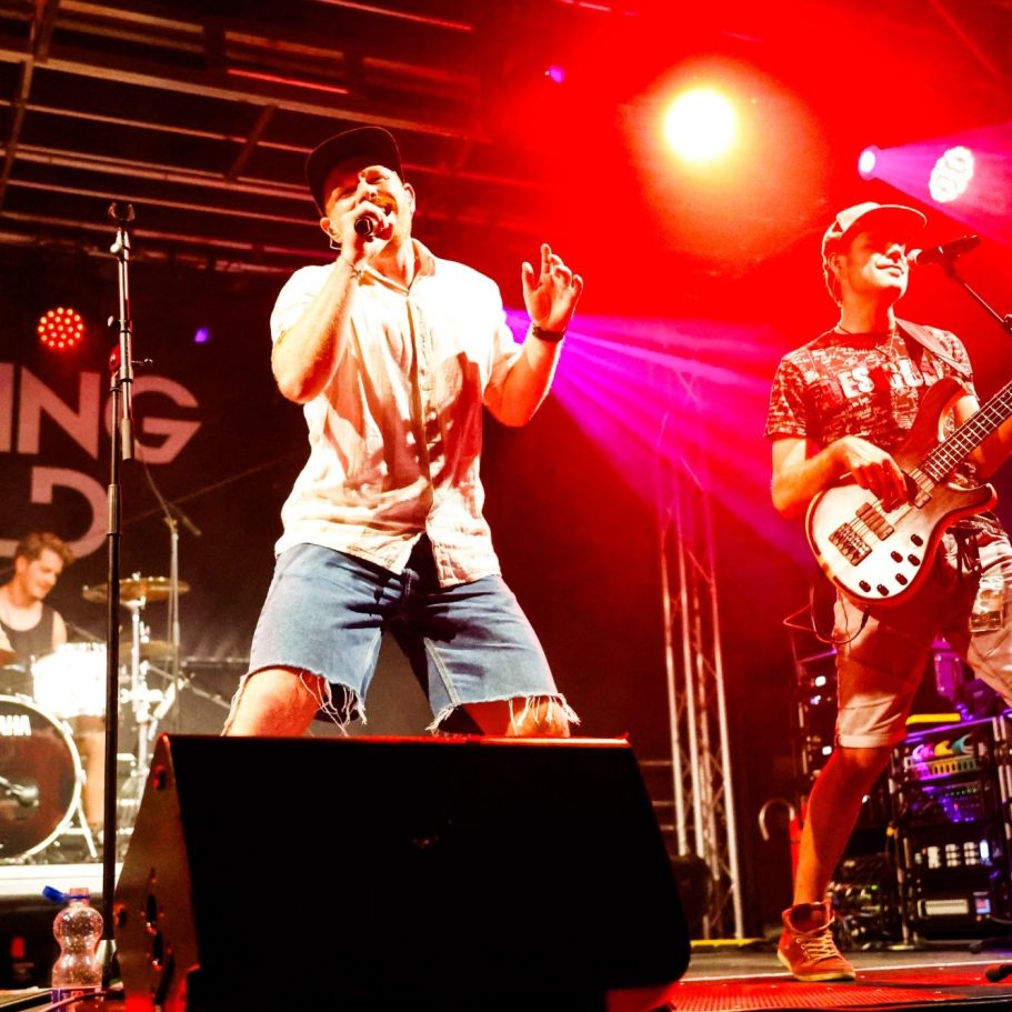 Band spielt live auf der Bühne mit bunten Lichtern und energetischen Performances.