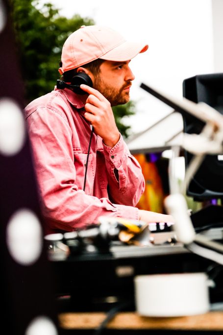 Ein DJ mit Kopfhörern, der an einem Mischpult arbeitet.