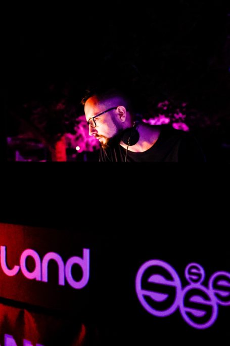 DJ an Pult mit bunten Lichtakzenten, konzentriert beim Auflegen.