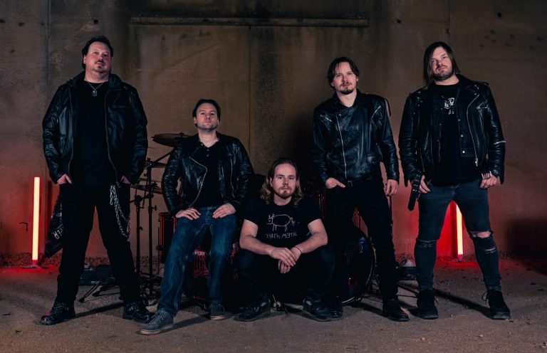 Fünf Musiker in Lederjacken posieren in einer druckvollen, dunklen Umgebung.