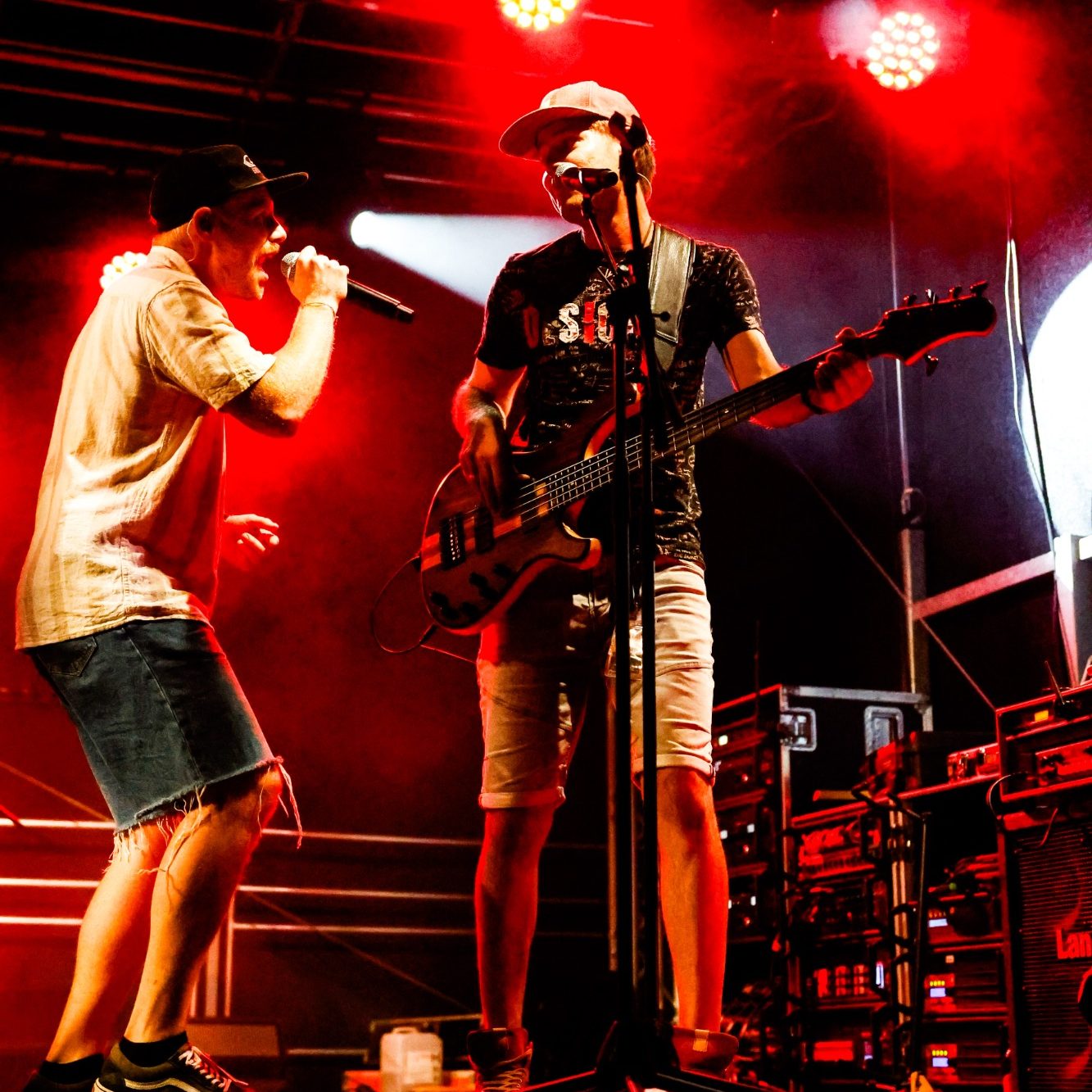 Zwei Musiker performen energetisch auf einer Bühne mit rotem Licht.