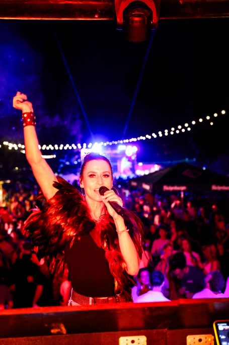 Frau singt leidenschaftlich vor begeistertem Publikum bei einem nächtlichen Festival.