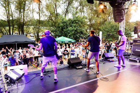 Band spielt auf einer Bühne vor jubelndem Publikum im Freien.