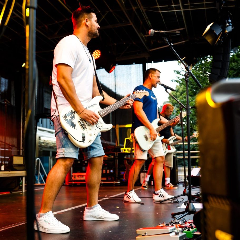 Zwei Musiker spielen elektrische Gitarren auf einer Bühne bei einem Live-Auftritt.