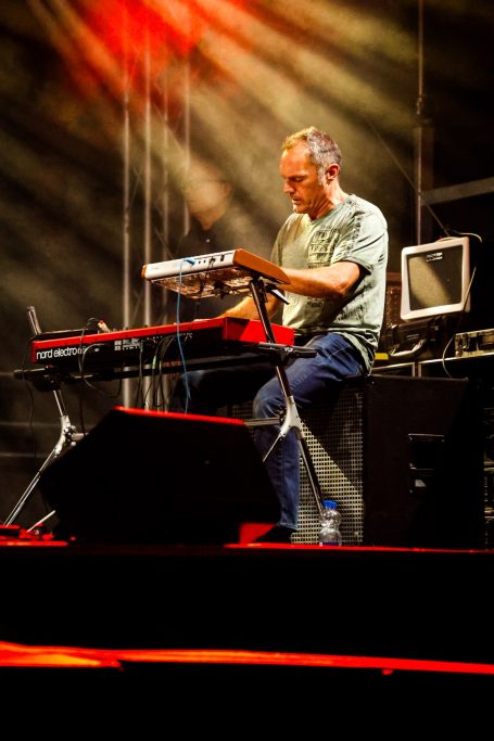 Ein Musiker spielt ein Keyboard auf einer Bühne mit Lichtern und Nebel.