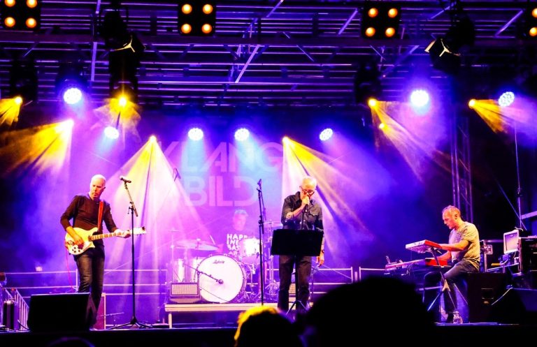 TORS Band spielt live auf einer Bühne mit bunten Lichtern und Nebel.